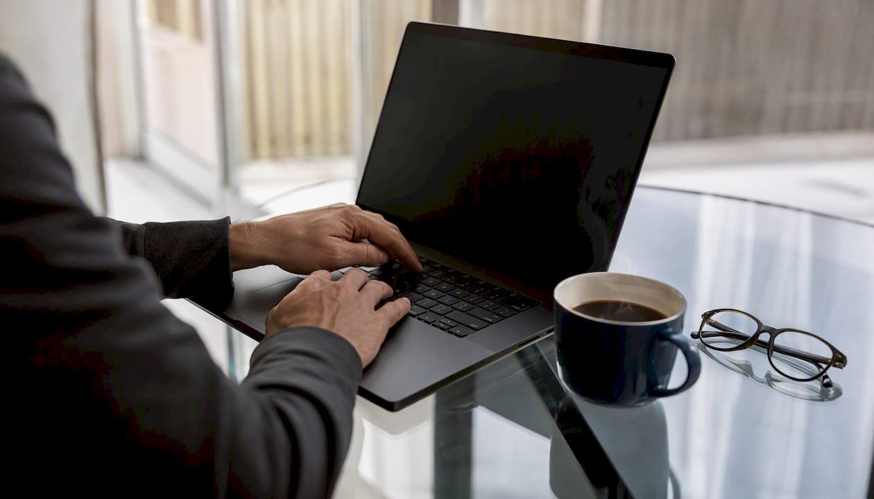 Hands interacting near laptop and coffee on table